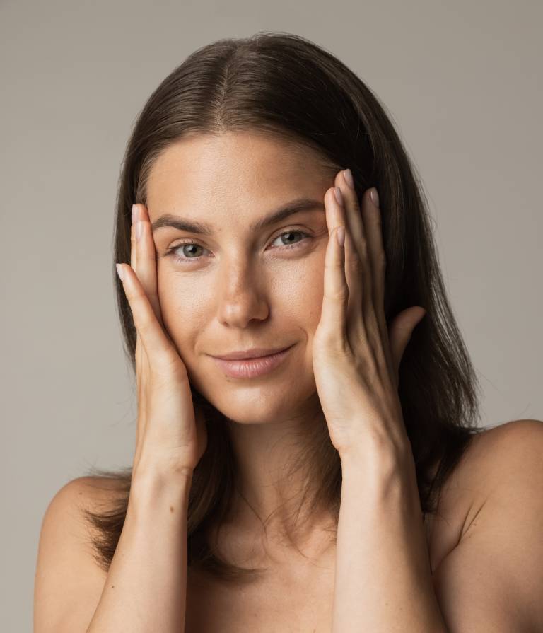 woman after full face aesthetics with hands on her face