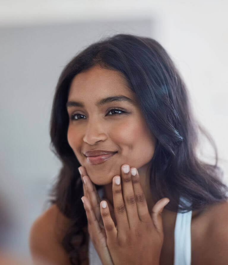 woman looking in mirror after dull skin treatment